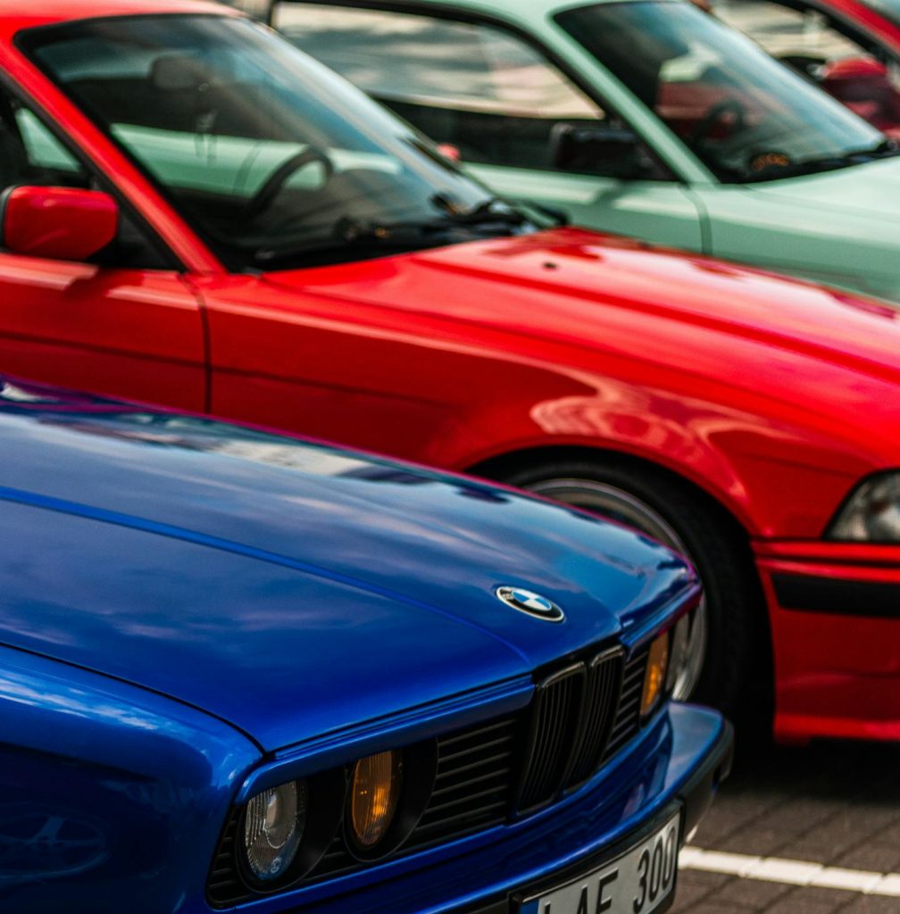 Colorful lineup of classic BMW cars parked outdoors in Lithuania.